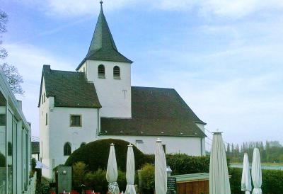 Ansicht aus Blickrichtung Südosten, außermittig eingestellter Kirchturm mit Knickhelm