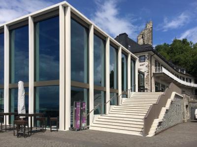 Neuer Glaskubus mit Bestandsbau und Ruine im Hintergrund