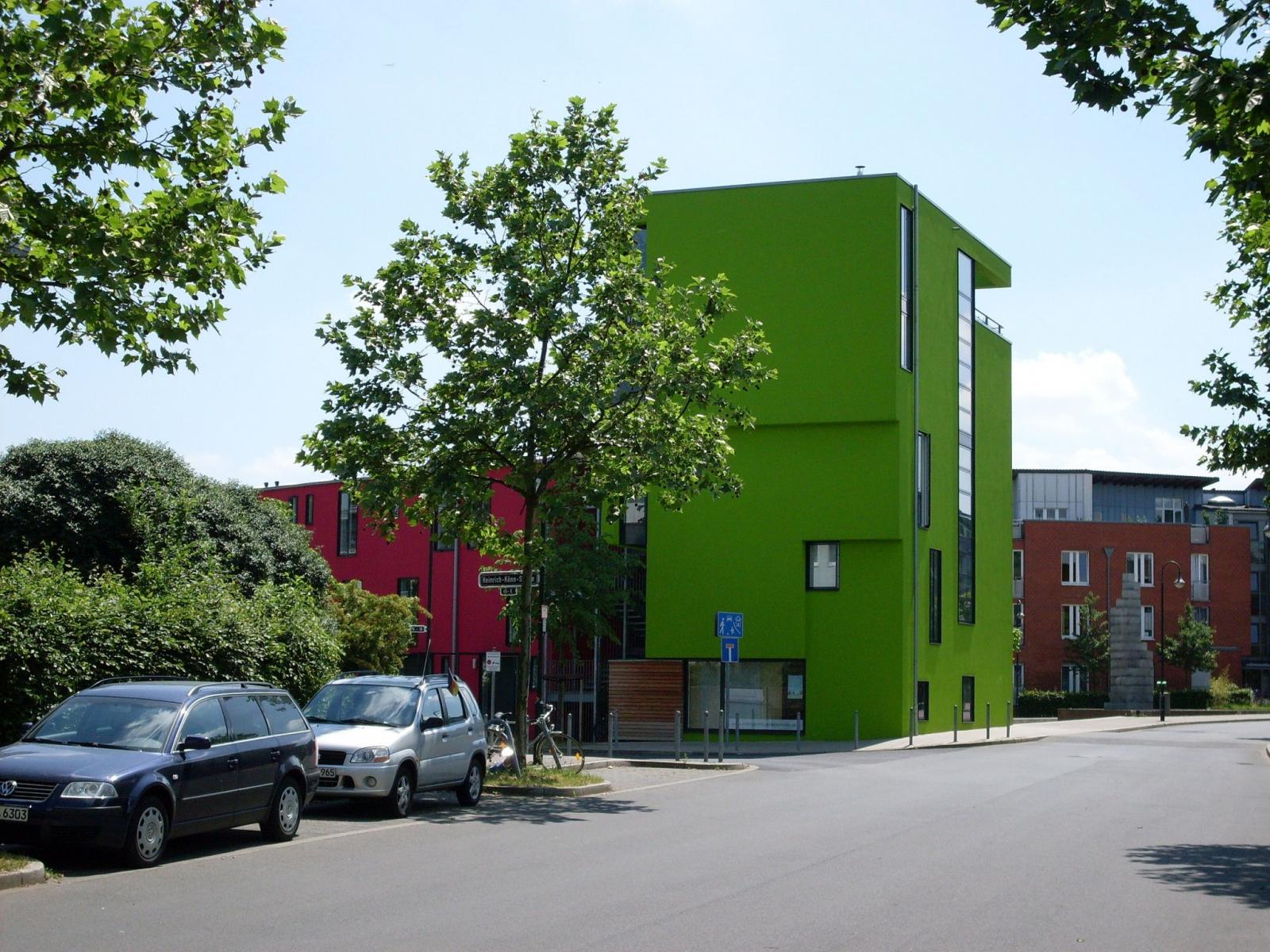 Nordwestansicht des leuchtend grünen Turmhauses mit rotem Langhaus im Hintergrund