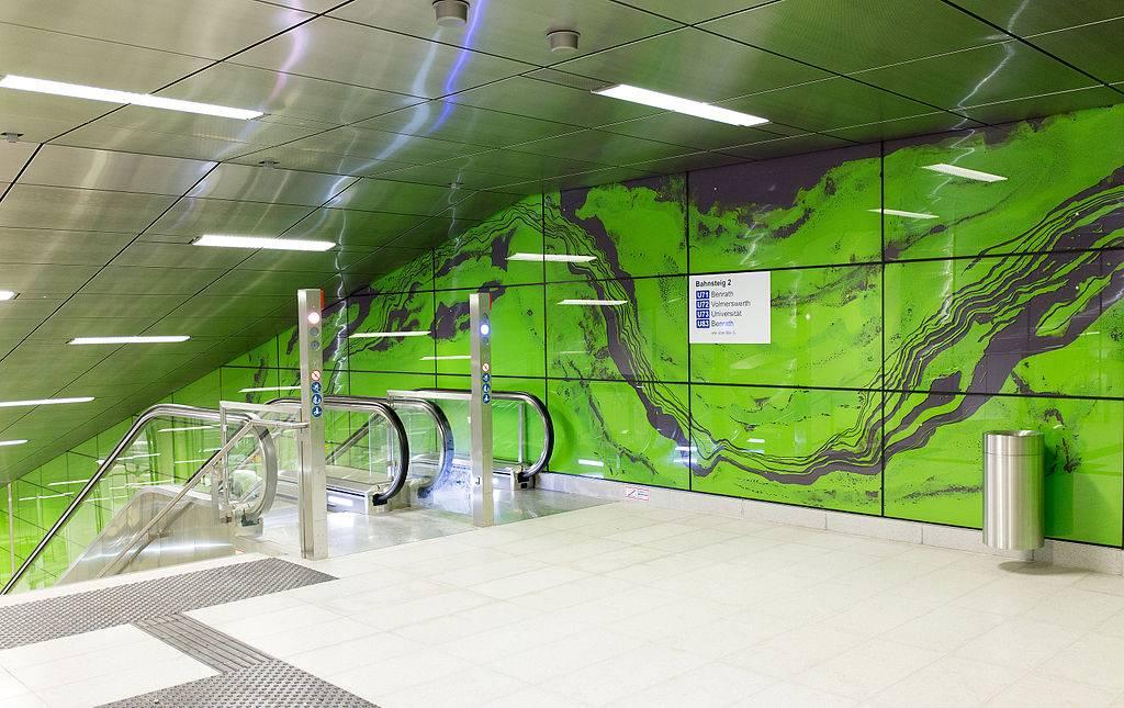 Haltestelle Graf-Adolf-Platz, Rolltreppe mit grüner Wandverkleidung "Achat" von M. Franke