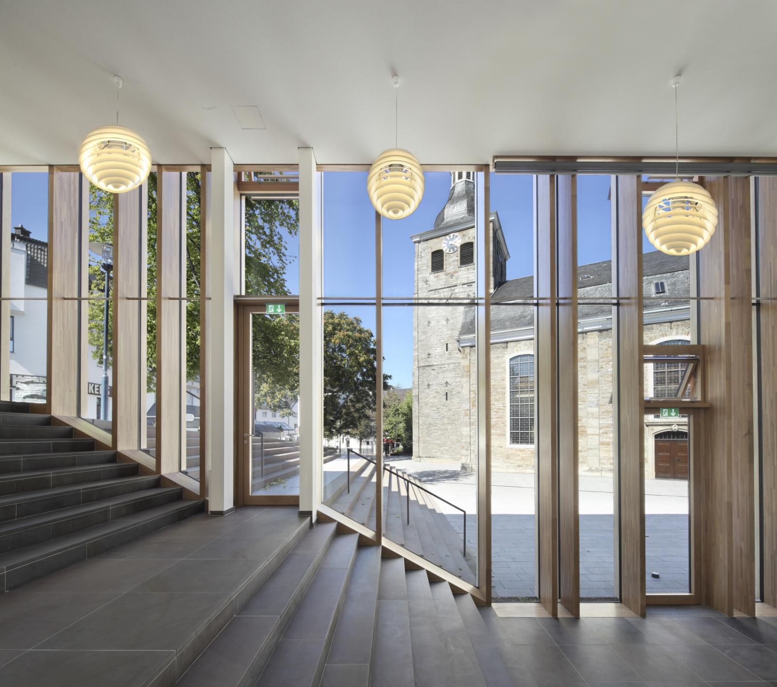 Blick von Innen durch die großen Fenster der Fassade nach außen zur Kirche